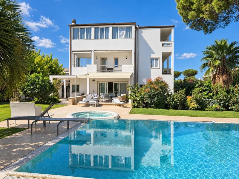 After: the same villa with clear blue pool water and no floats; house, garden and loungers unchanged
