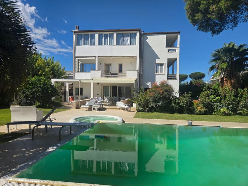 Before: three-story white villa with a pool of green, murky water and floats in it